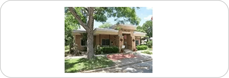 Small brick house with trees and lawn.