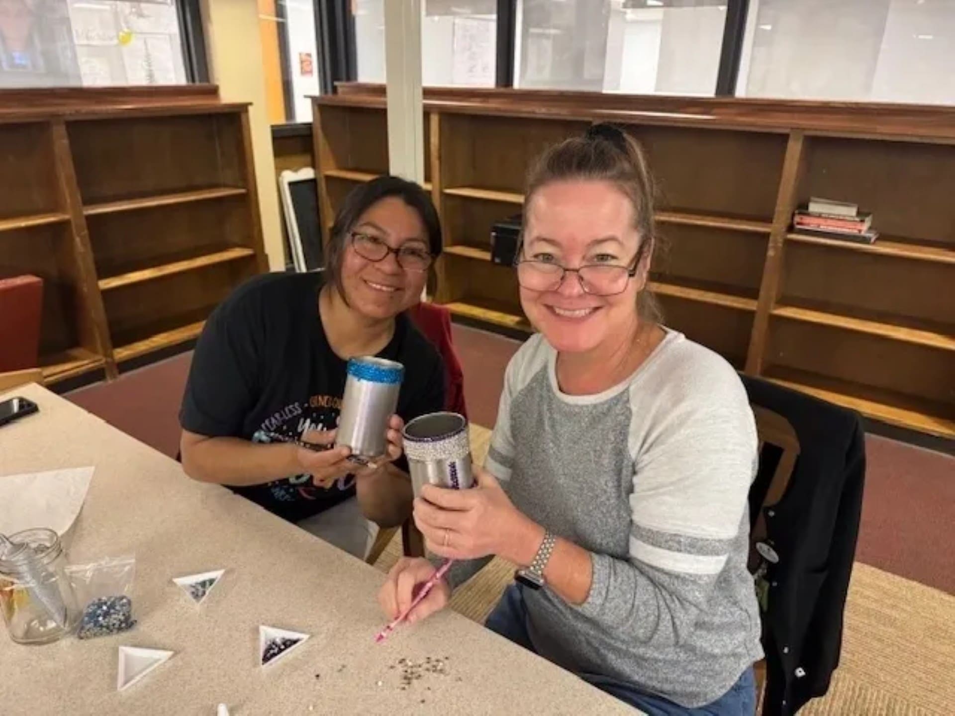 Two women crafting with smiles at table.