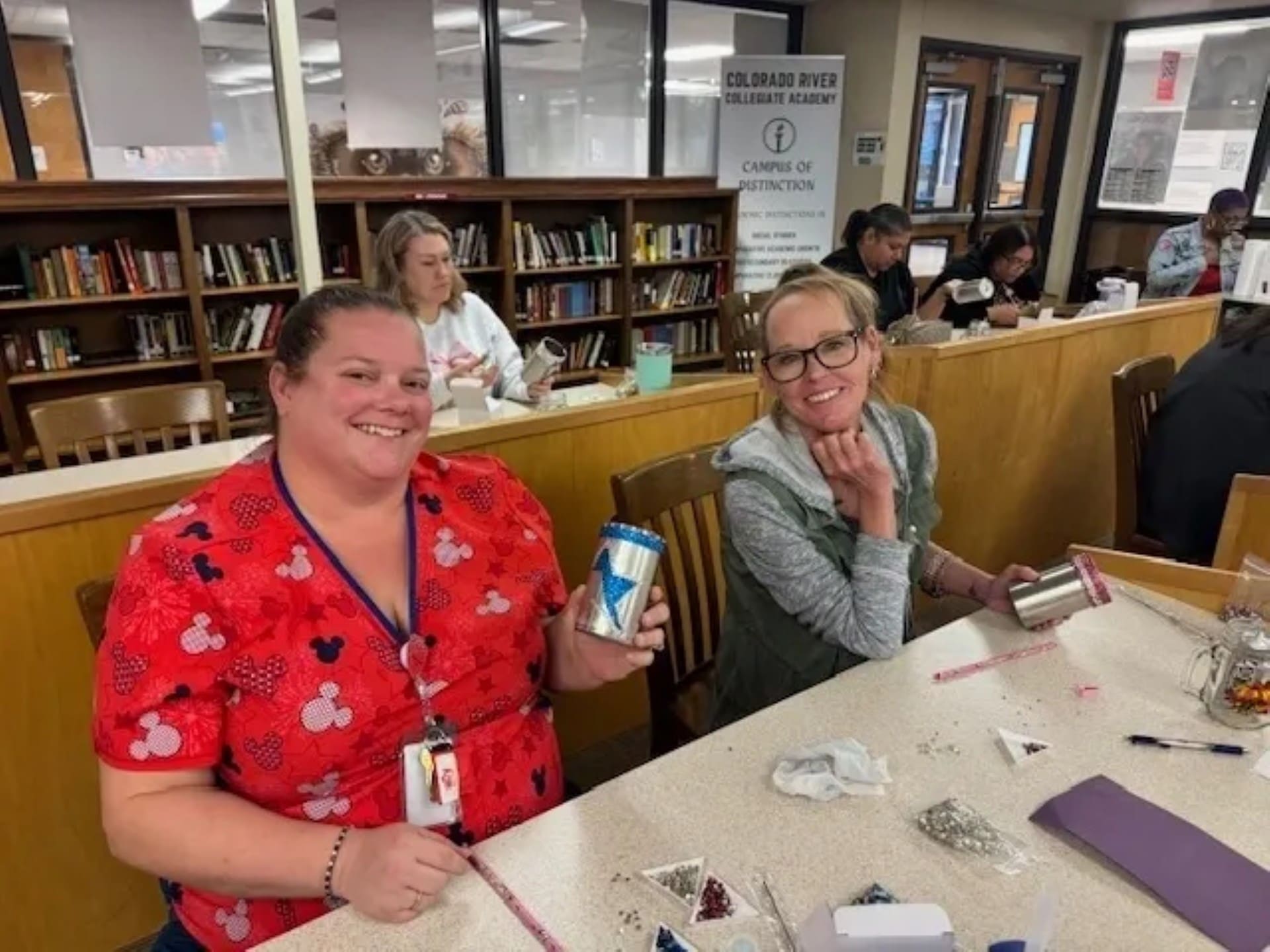 Two women crafting in a library setting.