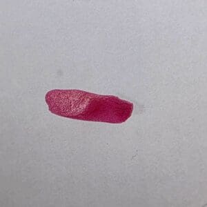Pink lipstick smear on white background.