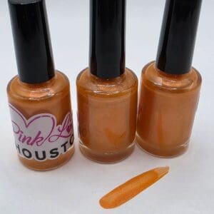 Three orange nail polish bottles with swatch.