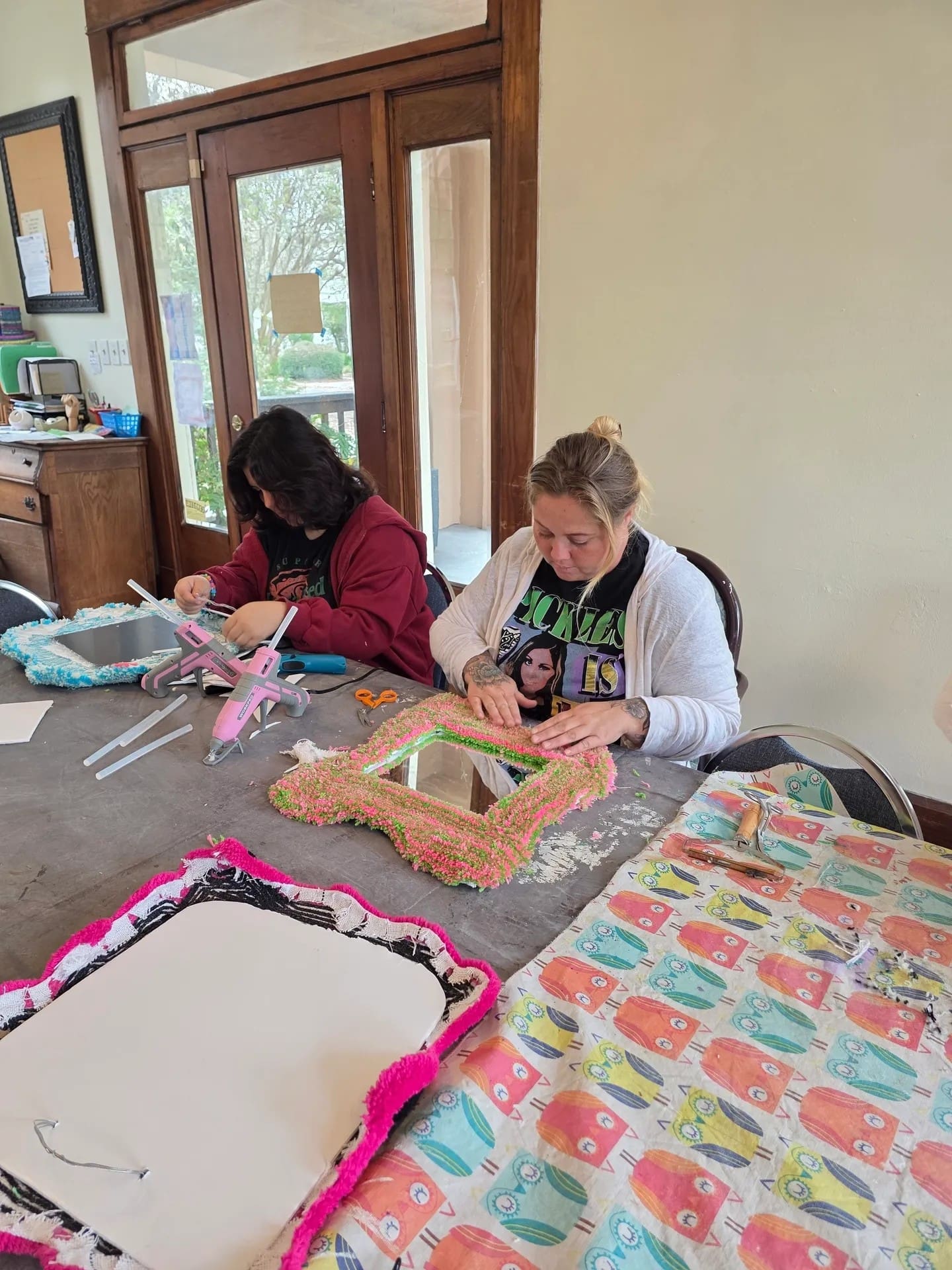 Two women crafting colorful picture frames.